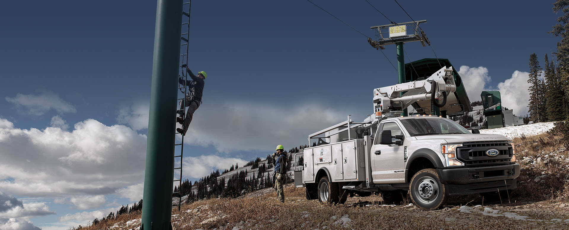 A Ford conversion body truck parked by a ski lift pole.