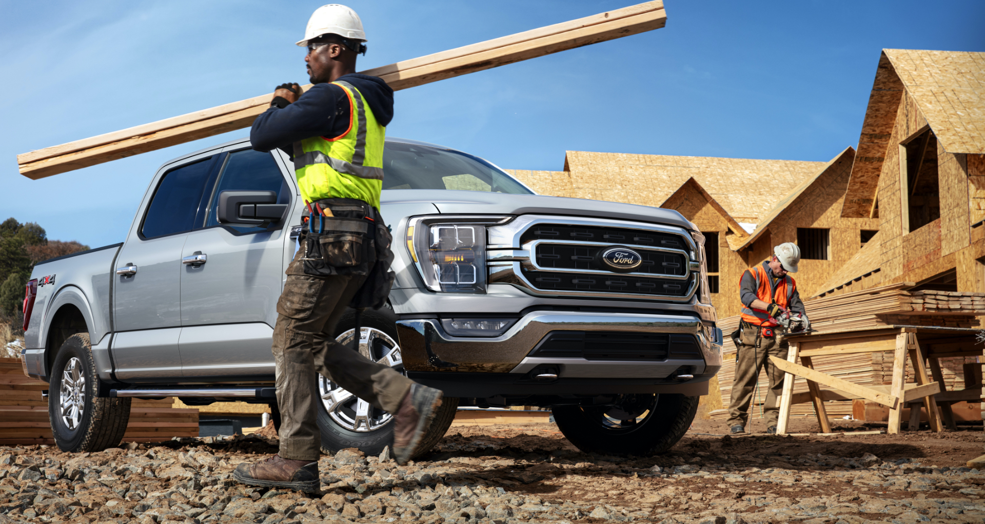 Construction workers are building a house and cutting OSB by a Ford F-150.