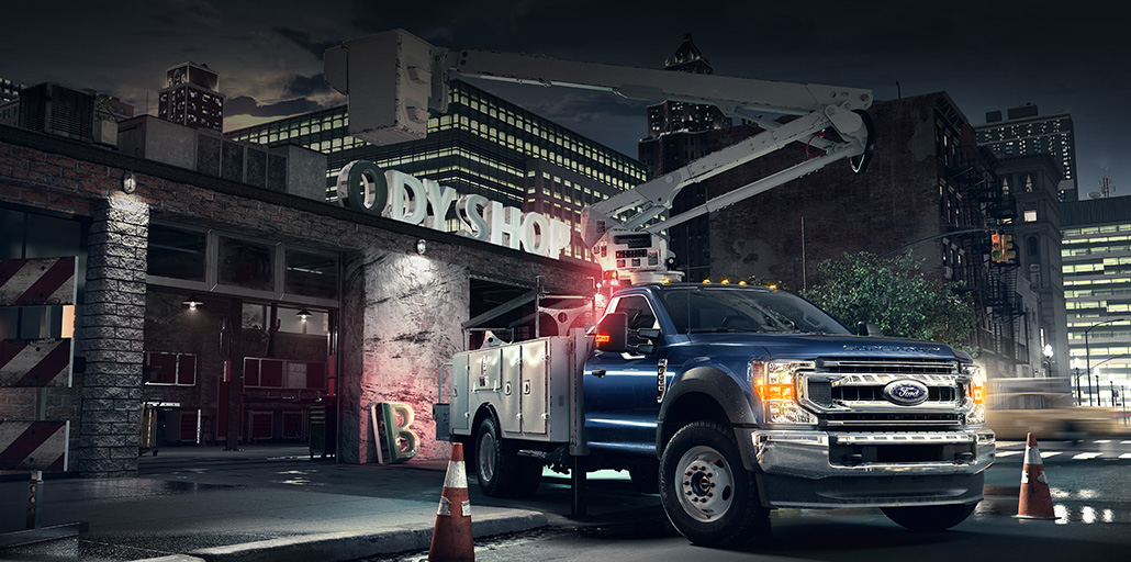 Ford Super Duty chassis with a bucket upfit parked at an office building.