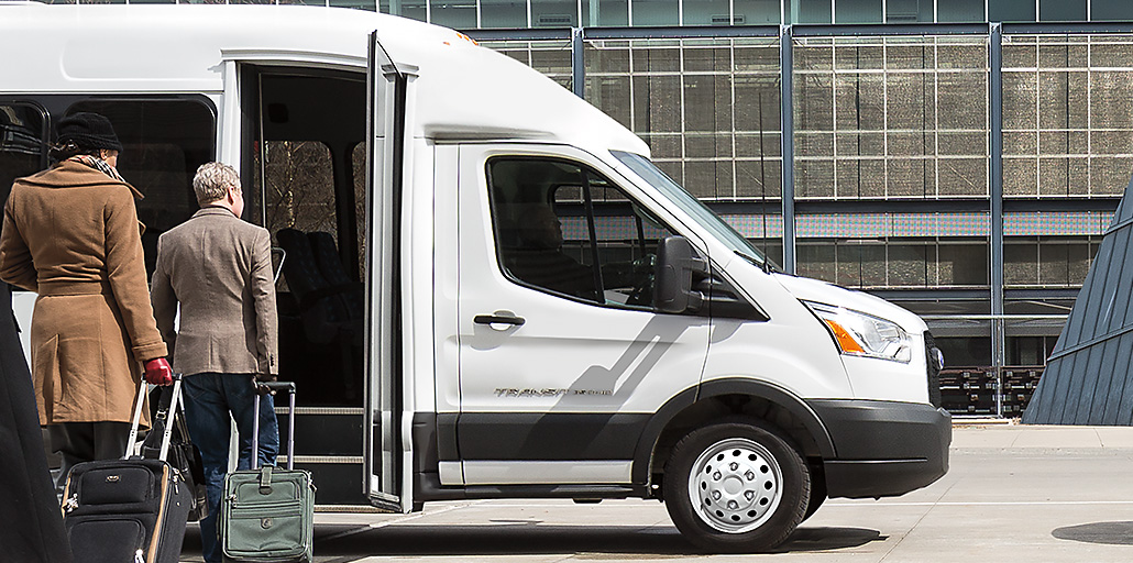 Two tourists exit a 2020 Ford Transit shuttle.